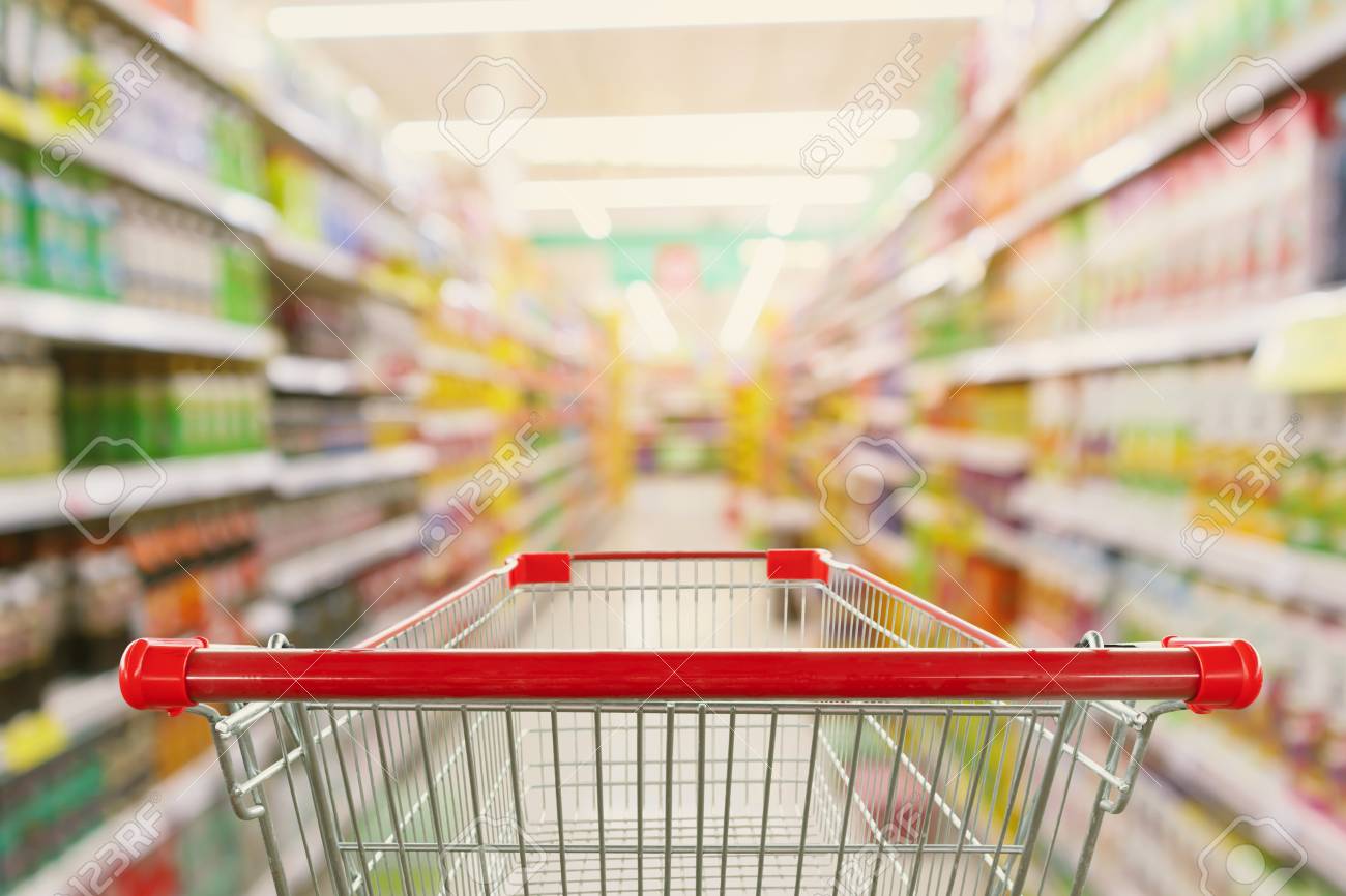 Supermarket aisle interior blur background with empty red shopping cart